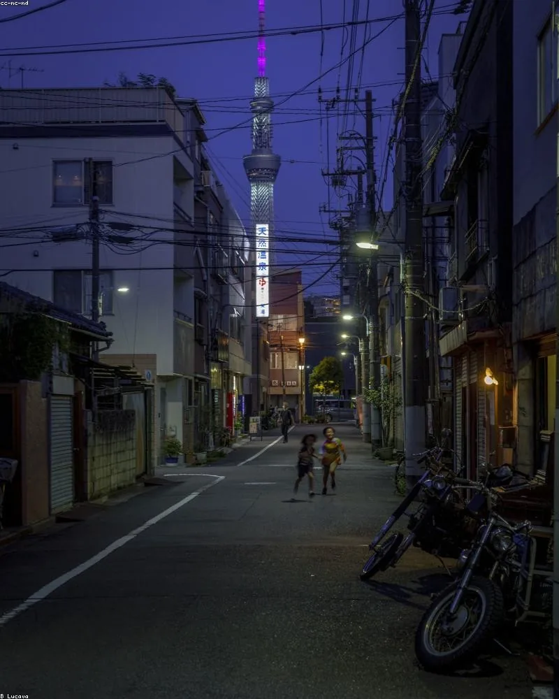 Evening street in a Japanese town with lanterns and parked bicycles under a violet sky