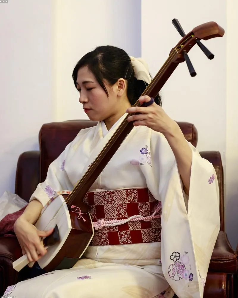 Woman in a white kimono playing the shamisen